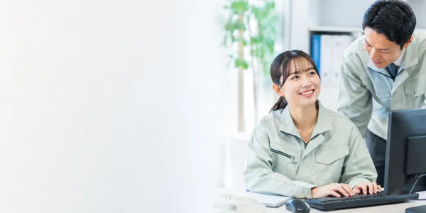 作業服姿の男女がPC作業中