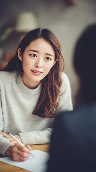 女性が対話しながらメモを取るシーン
