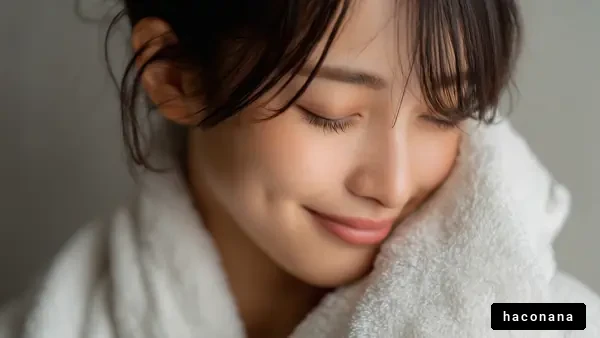 タオルを頬にあてた若い女性の笑顔